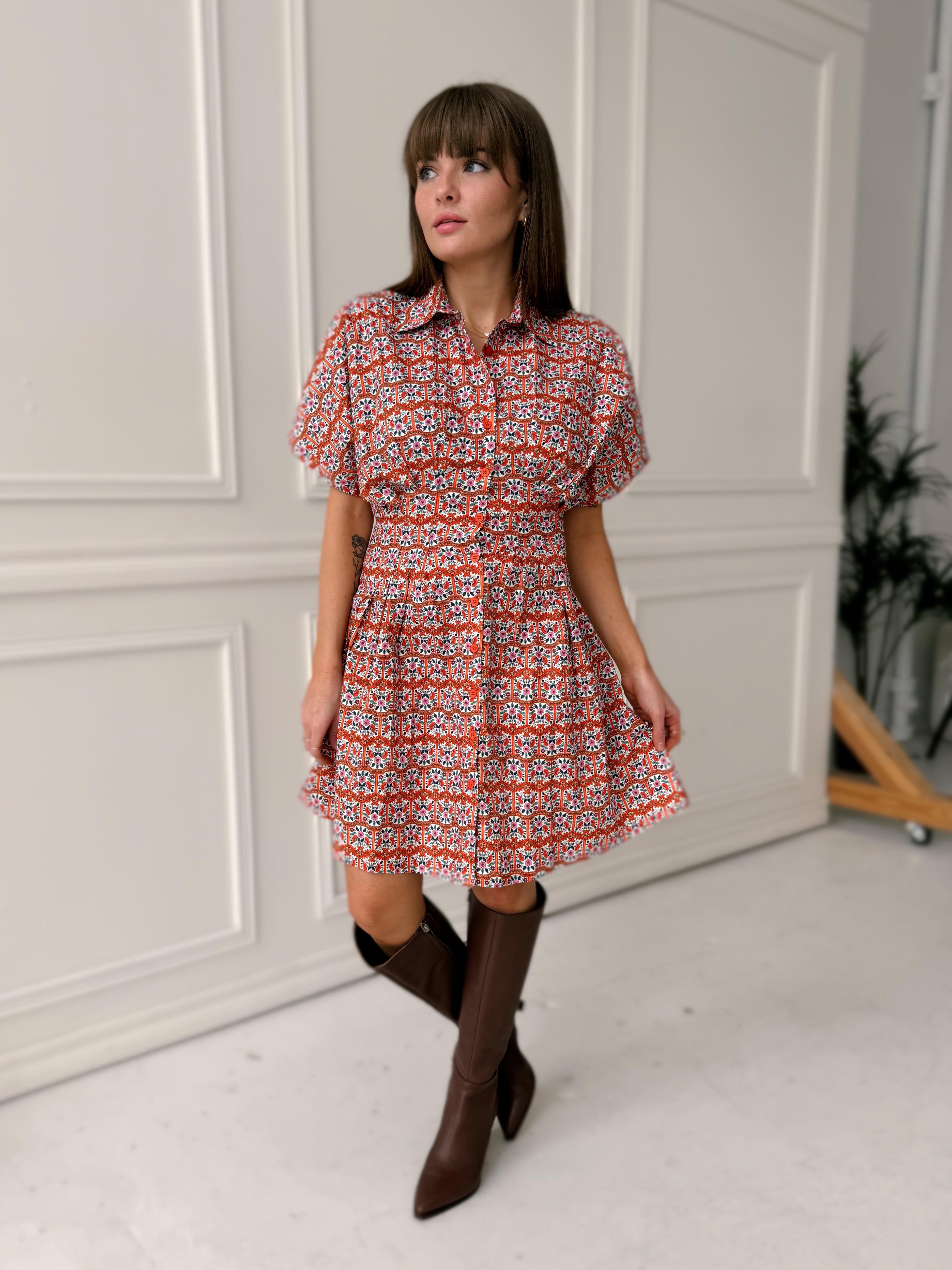 Woman in a patterned dress standing in front of a white door.