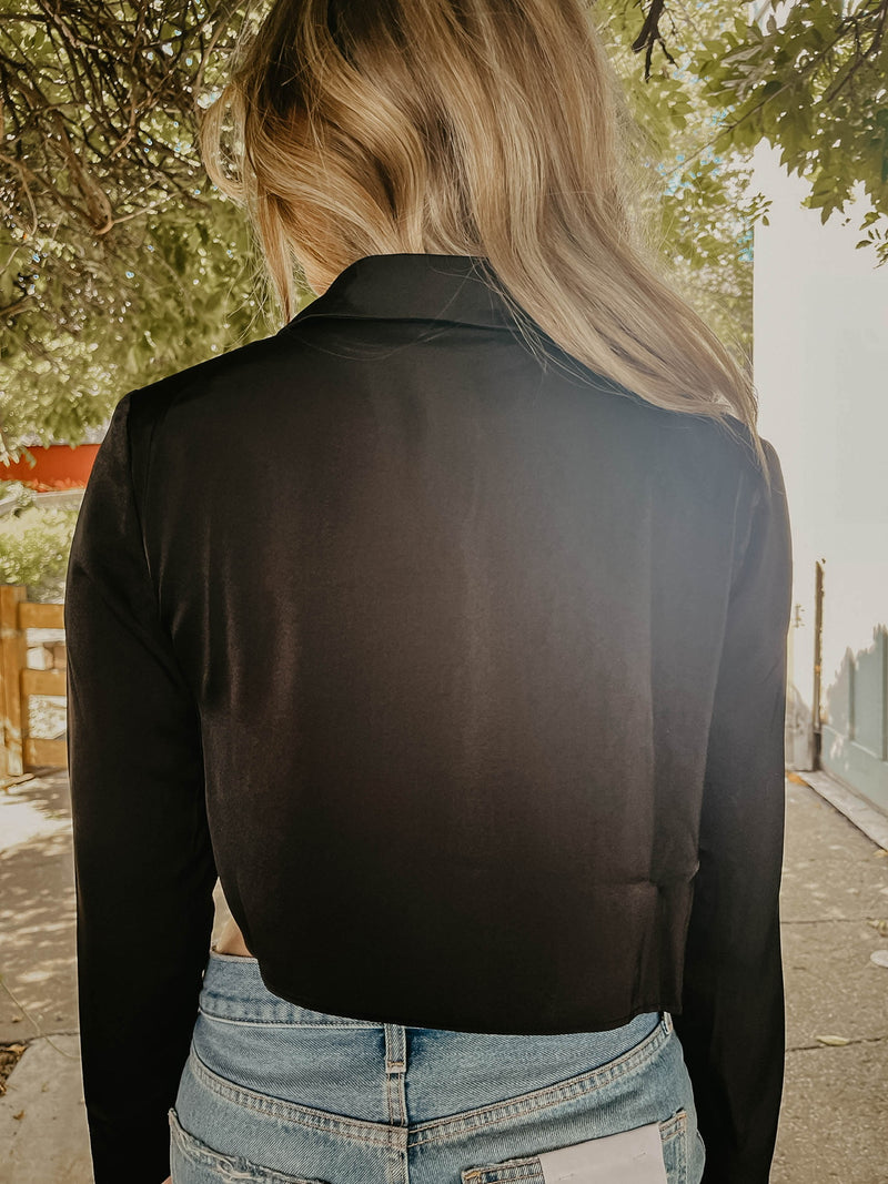 Model wearing black silk crop top, showing off the back.